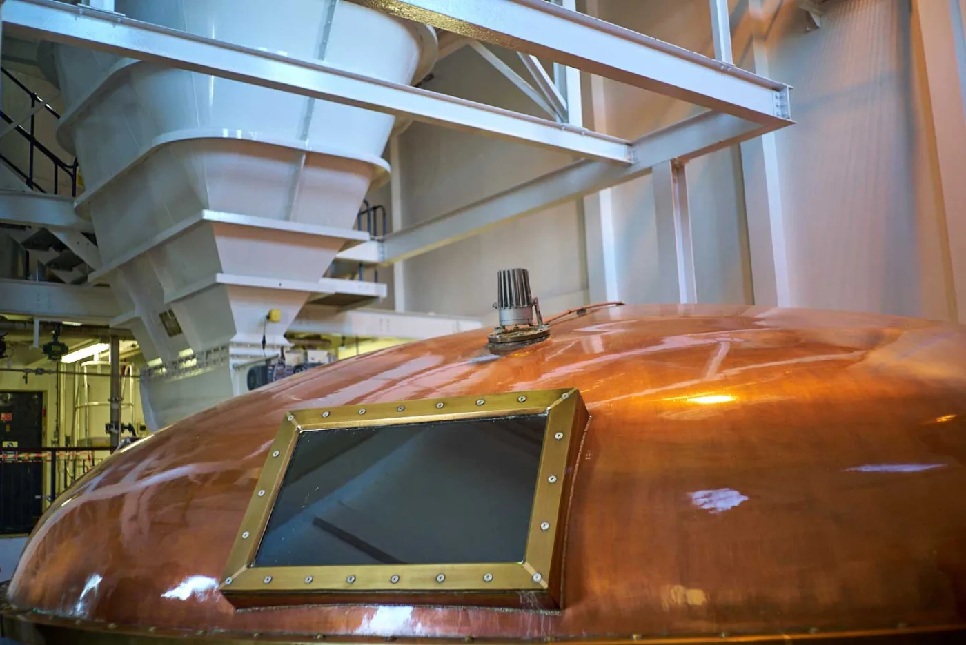 Il coperchio di rame del mash tun con un oblò e le tramogge del grist sopra