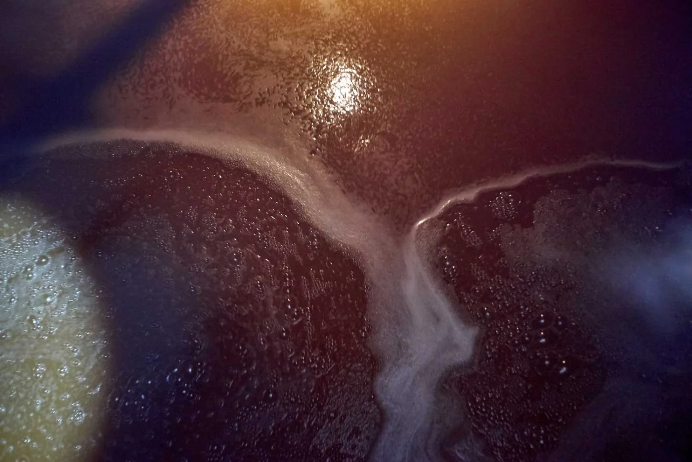 La superficie scura del wort in fermentazione con bolle e schiuma