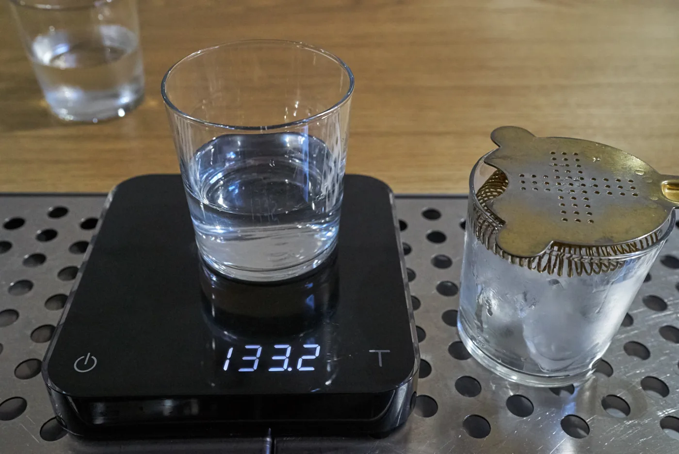 Bilancia digitale che segna 133,2 grammi accanto al mixing glass con i 6 cubetti residui e lo strainer