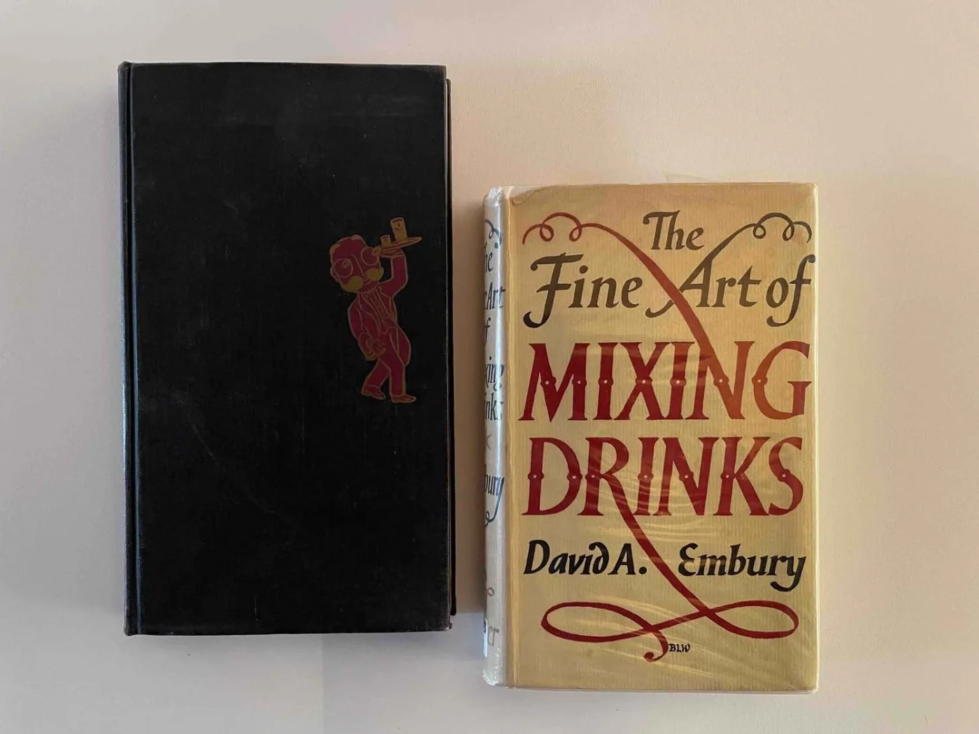Due copie di The Fine Art of Mixing Drinks di David A. Embury: una nera con il barman dorato e una con la sovraccoperta bianca e rossa