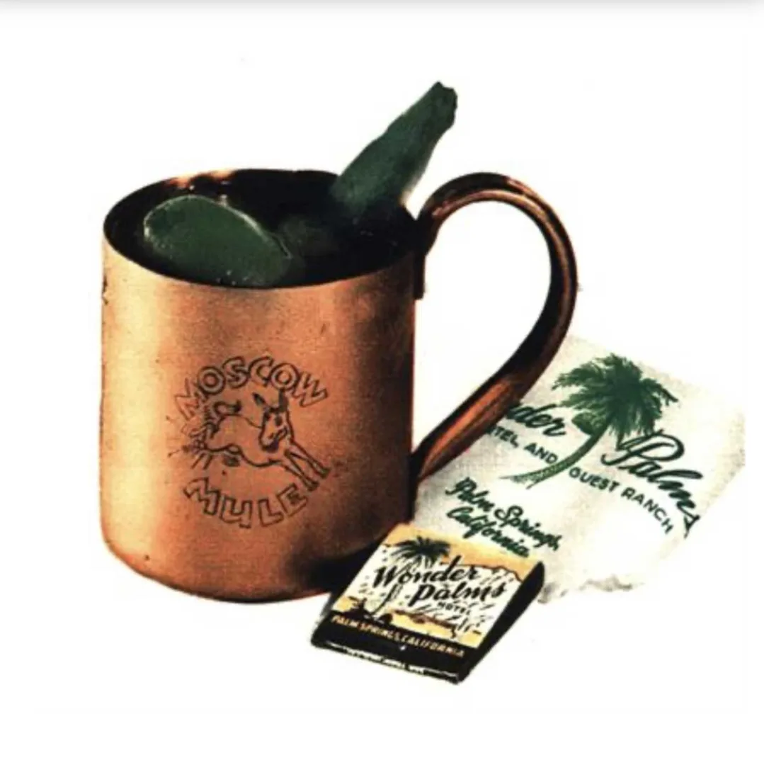 Tazza di rame Moscow Mule con lime e una striscia di cetriolo, accanto a un tovagliolo e una bustina di fiammiferi del Wonder Palms Hotel di Palm Springs
