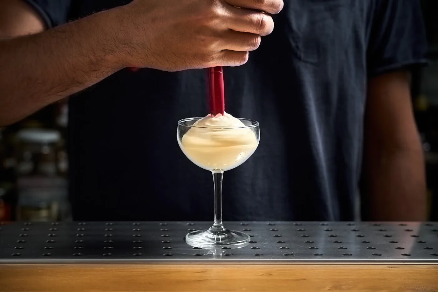 Una foam bianca e compatta erogata con il sifone su una coppetta da cocktail