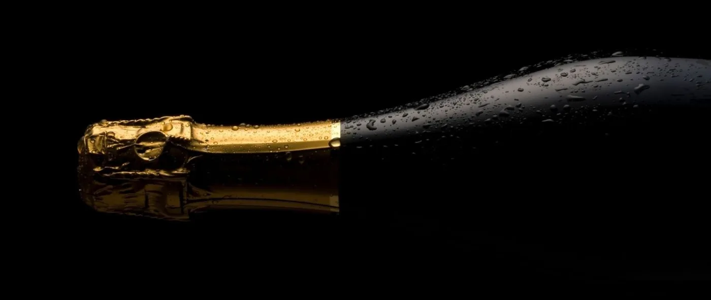collo di una bottiglia di vino frizzante con condensa su sfondo nero