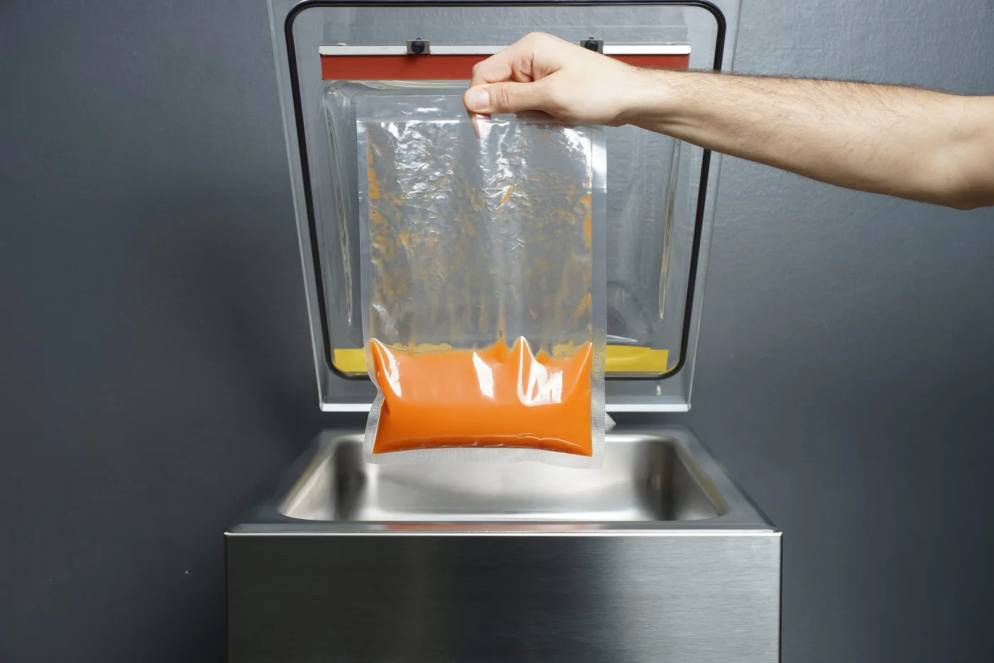 Sacchetto con liquido arancione sigillato sottovuoto, estratto dalla campana di una macchina professionale