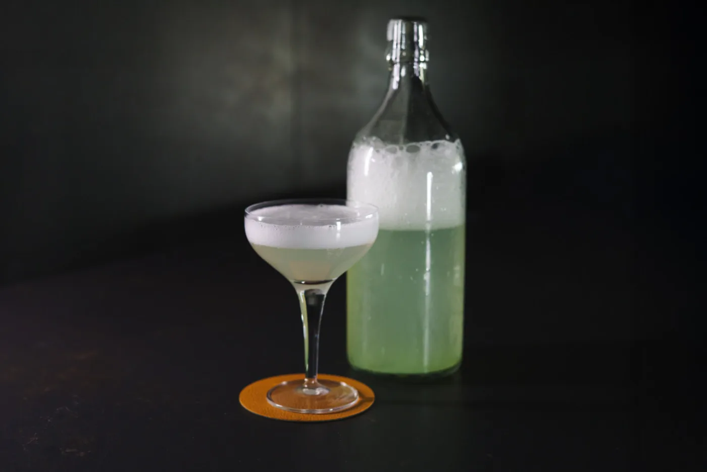 Bottiglia e bicchiere da cocktail con un fermentato di fiori di sambuco, usato come ingrediente del drink Hugo dal futuro